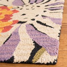 a close up of a colorful rug on a wooden floor with a wood table in the background