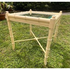 a table with glass top sitting in the grass next to a potted planter