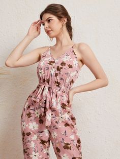 The pink base makes up any mood for an outing. The Floral Print Cami Jumpsuit also comes with a matching belt that cinches at the waist to accentuate your curves and create a flattering silhouette. The bold and vibrant floral print adds a pop of color and makes this jumpsuit perfect for any occasion, whether it's a brunch date with friends or a day out exploring the city. Features: Pattern Type: Floral, All Over Print Details: Belted, Wrap Length: Capris Type: Cami Fit Type: Regular Fit Neckline Pink Printed V-neck Jumpsuits And Rompers, Chic Pink Floral Print Jumpsuit, Summer Pink Floral Print Jumpsuit, Chic Pink Floral Print Jumpsuits And Rompers, Summer Pink Floral Jumpsuits And Rompers, Summer Pink Floral Print Jumpsuits And Rompers, Feminine Floral Print Jumpsuits And Rompers For Beach, Summer Floral Print Pink Jumpsuit, Pink Feminine Jumpsuits And Rompers For Summer