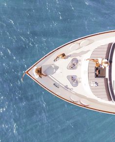 an aerial view of a white boat in the blue water with two people on it