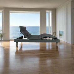 a bed sitting on top of a hard wood floor in front of large open windows