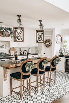 a kitchen with black and white tile flooring and wooden chairs in front of an island