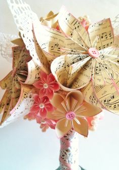 a vase filled with paper flowers and musical notes on it's sides, sitting on a table