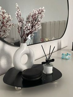 a white vase with flowers in it sitting on a table next to a brush holder