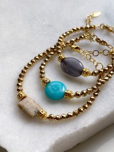 JAYA Bracelet Material: Jade, African Opal, Agate, Hematite, Gold plated brass, Steel parts Dimensions: 17cm +5cm extender chain / 6.7in +2in extender chain AGATE-Grey JADE-Turquoise OPAL-Beige ⛦Natural Semi-precious Stones ⛦Adjustable Length ⛦Delivered in a fabric pouch ⛦Handcrafted in our workshop in Athens and Limnos Island ⛦Follow us on instagram: @puregreekshop All PURE GREEK Jewels are inspired from the ancient greek arts, folklore traditions and world cultures. Our jewelry are handmade with love and imagination so you can enjoy unique creations.  I use mineral and semi-precious stones, crystals, real pearls, gold plated brass metal, wooden elements, greek and oriental charms, pompons and feathers. I only use high quality materials that guarantee great comfort and longevity to our je Semiprecious Stone Bracelet, Gold Agate Crystal Bracelet Gift, Bohemian Gold Crystal Stackable Bracelet, Gold Bohemian Beaded Bracelets With Gemstones, Bohemian Gold Crystal Bracelet With Natural Stones, Gold Bohemian Crystal Bracelet With Natural Stones, Turquoise Beaded Charm Bracelet For Gift, Turquoise Crystal Bangle Bracelet As Gift, Turquoise Beaded Charm Bracelet Gift