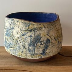 a blue and white bowl sitting on top of a wooden table next to a wall