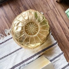 a gold poufce sitting on top of a wooden floor next to a rug