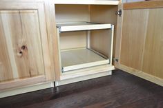 an open cabinet door in a kitchen with wood floors