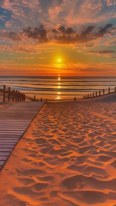 the sun is setting over the beach and boardwalks that lead to the water's edge