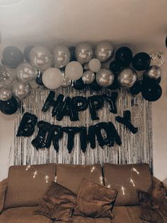 a birthday party with balloons and streamers hanging from the ceiling over a couch in front of a wall