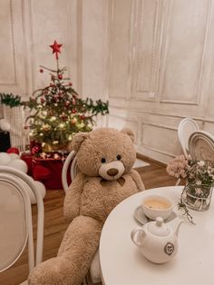 a teddy bear sitting at a table with a cup of coffee