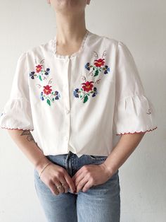 Beautiful white handmade blouse with lace at the neck, flared puff sleeves and stunning embroidery flowers. Size and fabric unknown, most likely cotton-polyester blend. The blouse will fit size S (on a pictures) up to L/XL. Measurement, single flat lying: Shoulders 42 cm Chest 54 cm Length 59 cm Feminine Puff Sleeve Blouse With Floral Embroidery, Cotton Embroidered Puff Sleeve Blouse, Vintage Cotton Peasant Top With Short Sleeves, Fitted Puff Sleeve Top With Floral Embroidery, White Puff Sleeve Blouse With Floral Embroidery, Fitted Embroidered Top With Puff Sleeves And Floral Design, Fitted Embroidered Top With Puff Sleeves, Fitted Cotton Embroidered Top With Puff Sleeves, Cotton Blouse With Embroidered Puff Sleeves