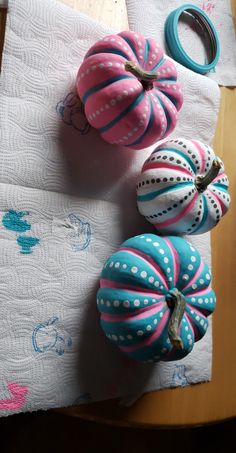 three decorative pumpkins sitting on top of a wooden table next to scissors and napkins