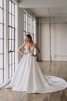 a woman in a white wedding dress standing on a wooden floor with her hands on her hips