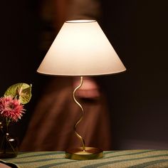 a lamp that is sitting on a table next to a vase with flowers in it