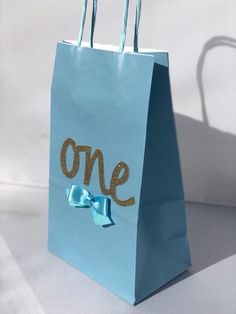 a blue shopping bag with the word one painted on it and a blue ribbon tied around it