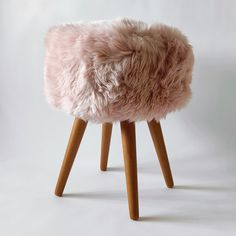 a small stool with wooden legs and a pink fur seat cover on top of it