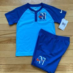 This Nike 2-Piece Graphic Set Is Perfect For Any Young Athlete Or Casual Wearer. The Set Includes A Blue Cotton Blend T-Shirt With A Graphic Logo And A Pair Of Shorts With An Elastic Waistband For A Comfortable Fit. The Shorts Also Feature A Crew Neck And Short Sleeves, Making Them Ideal For Warmer Seasons And Activities. The Set Is Machine Washable And Easy To Care For, Ensuring A Long-Lasting Addition To Any Young Boy's Wardrobe. The Nike Logo Adds A Touch Of Athletic Wear To The Outfit, While Short Cotton Tops For Sports, Sportswear Tops For Playwear, Short Sleeve Sportswear Tops For Play, Nike Sports Sets With Short Sleeve, Nike Sports Set With Short Sleeves, Nike Blue Shorts For Sports Events, Nike Short Sleeve Sports Sets, Cotton Sportswear Shorts For Playwear, Cotton Sports Sets With Short Sleeves