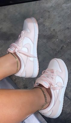 a woman's legs with pink nike shoes and gold chain bracelets on them