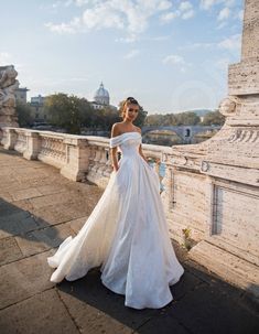 a woman in a white wedding dress standing on a bridge