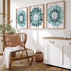 a living room with three paintings on the wall and a wicker chair in front of it