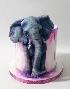 there is a cake that looks like an elephant on top of a stand with pink and blue icing