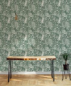 a wooden table sitting on top of a hard wood floor next to a potted plant