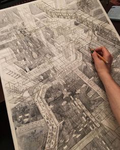 a person is drawing an aerial view on a piece of paper with a pencil in their hand