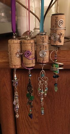 some wine corks are hanging on the wall with beads and other items attached to them