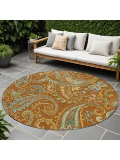 an outdoor area rug is shown in front of a couch and potted planter