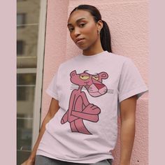 Here it is, the **Pink Panther Shirt** - a perfect blend of retro charm and modern style! Celebrate the timeless elegance of the iconic Pink Panther with this fabulous t-shirt, designed to bring a touch of fun and nostalgia to any wardrobe. This playful and vibrant design makes for an ideal gift, combining cozy comfort with the classic comic appeal of the beloved Pink Panther. Crafted from premium, soft fabric, this shirt offers a luxurious feel while ensuring durability for everyday wear. The h Trendy Pink T-shirt With Character Print, Casual Pink T-shirt For Fan Merchandise, Pink Relaxed Fit Tops With Cartoon Print, Pink Cartoon Print Tops With Relaxed Fit, Pink Cartoon Print Top With Relaxed Fit, Pink Cartoon Print Top In Relaxed Fit, Pink Retro Shirt With Relaxed Fit, Fun Pink Shirt With Cartoon Print, Retro Pink T-shirt With Cartoon Print