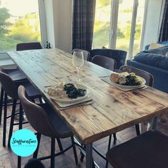 a wooden table with plates of food and wine glasses on it in front of a couch