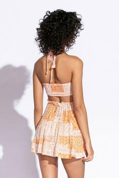 STYLE INFORMATION: Get your Texas boho vibes on in the Sundown Orange Patchwork Print Sundress!. Orange patchwork print woven fabric shapes this cute dress that has a halter V-neckline with tie straps, and a cutout waist.. The open back wraps around to the sides to create a cutout effect above the attached mini skirt. Ruffle trim and side ties decorate the cutout waist. DETAILS & CARE: Rayon/Polyester. Dry Clean. Imported. SHIPPING: Orders are processed within 1-2 business days. Packages are shi Summer Vacation Halter Top With Tie Straps, Sleeveless Tie Back Halter Top For Brunch, Summer Halter Top With Tie Straps, Sleeveless Halter Dress With Crisscross Straps For Vacation, Summer Beach Halter Dress With Crisscross Straps, Spring Mini Length Halter Dress With Smocked Back, Spring V-neck Halter Top With Tie Back, Bohemian V-neck Halter Top For Summer, Spring Halter Dress With Crisscross Straps And V-neck