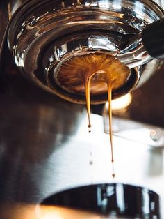 syrup being poured into a glass jar on top of a metal counter with the lid open