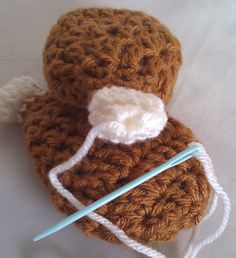 a crocheted brown object with a white ball of yarn on top of it