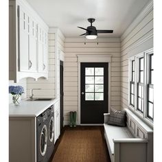 a washer and dryer in a room with white walls, wood floors and black door