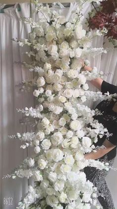 a woman standing next to a tall white flower arrangement