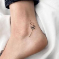 a small dandelion tattoo on the ankle that is sitting on someone's leg