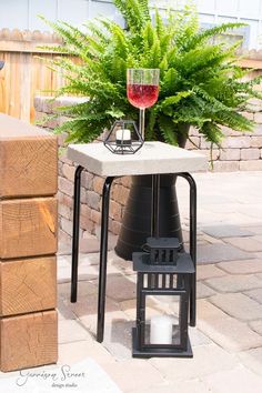 a small table with a candle on it next to a potted plant and a glass of wine