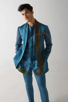 Teal blue linen silk blazer with an olive flap and net detailing, including colorful thread and gold zari hand embroidery.
Component: 1
Pattern: Hand embroidered
Type Of Work: Thread, Gold zari
Neckline: Shawl lapel
Sleeve Type: Full
Fabric: Linen silk
Color: Blue
Other Details: 
Side pockets
Note : Kurta and pant worn by the model are not for sale.
Occasion: Party - Aza Fashions Designer Tailored Outerwear For Festive Occasions, Designer Tailored Outerwear For Festive Season, Fitted Blue Outerwear For Designer Wear, Blue Fitted Outerwear For Designer Wear, Silk Fitted Bandhgala With Dupatta, Designer Embroidered Nehru Jacket In Raw Silk, Formal Blue Embroidered Outerwear, Elegant Blue Designer Outerwear, Festive Blue Blazer For Semi-formal Occasions