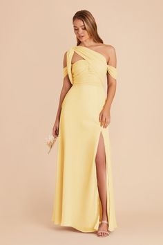 a woman wearing a yellow dress with one shoulder and slited leg, standing in front of