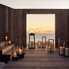 an outdoor area with candles and lanterns in front of the ocean