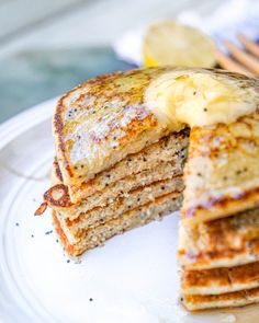 a stack of pancakes sitting on top of a white plate covered in butter and syrup