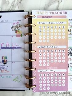 a planner is open on top of a marble table with the words habit tracker written in it