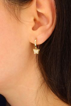 Crafted with elegance and charm, these 14K Gold Butterfly Dangle Hoop Earrings are a delicate and stylish accessory for any occasion. The intricate design features fluttering butterfly charms hanging gracefully from the gold hoops, adding a whimsical touch to your look. Made from high-quality 14K gold, these earrings offer a luxurious shine that catches the light beautifully. Perfect for adding a touch of nature-inspired beauty to your ensemble, these earrings are versatile and eye-catching. Whe Elegant Huggie Earrings With Butterfly Charm, Butterfly Charm Huggie Earrings As Gift, Elegant Huggie Jewelry With Butterfly Charm, Dainty Hoop Earrings With Butterfly Charm, Gold Dainty Hoop Earrings With Butterfly Charm, Fluttering Butterfly, Dangle Hoop Earrings, Gold Butterfly, Butterfly Charm