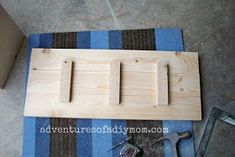 some tools are laying out on the floor next to a wooden board with three pegs