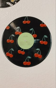 an old record with cherries on it hanging from the wall next to a clock