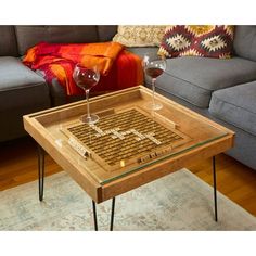 a coffee table with two wine glasses on it in front of a couch and rug