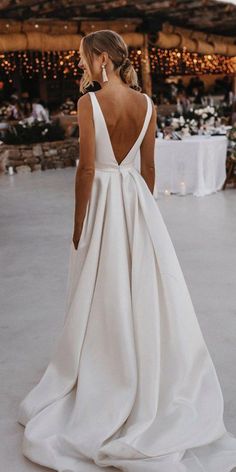 a woman in a white wedding dress looking back at the camera while standing on a dance floor