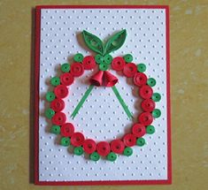 a handmade card with red and green buttons in the shape of a wreath on a white background